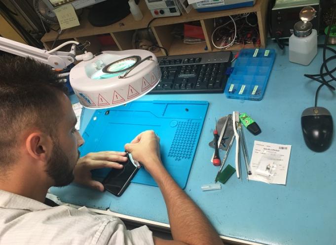 Répération d'un smartphone dans l'atelier de Sofi Groupe. crédit : Sofi Groupe. 